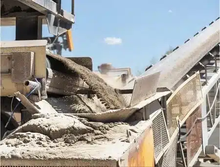 Conveyor belt dumping sandy aggregate into a pile at a quarry or processing plant site
